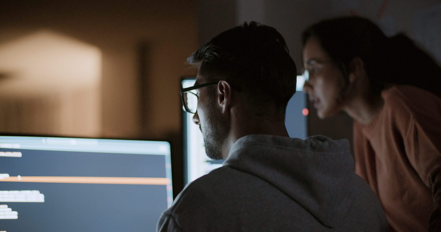 Man in gray sweatshirt looks at computer screen
