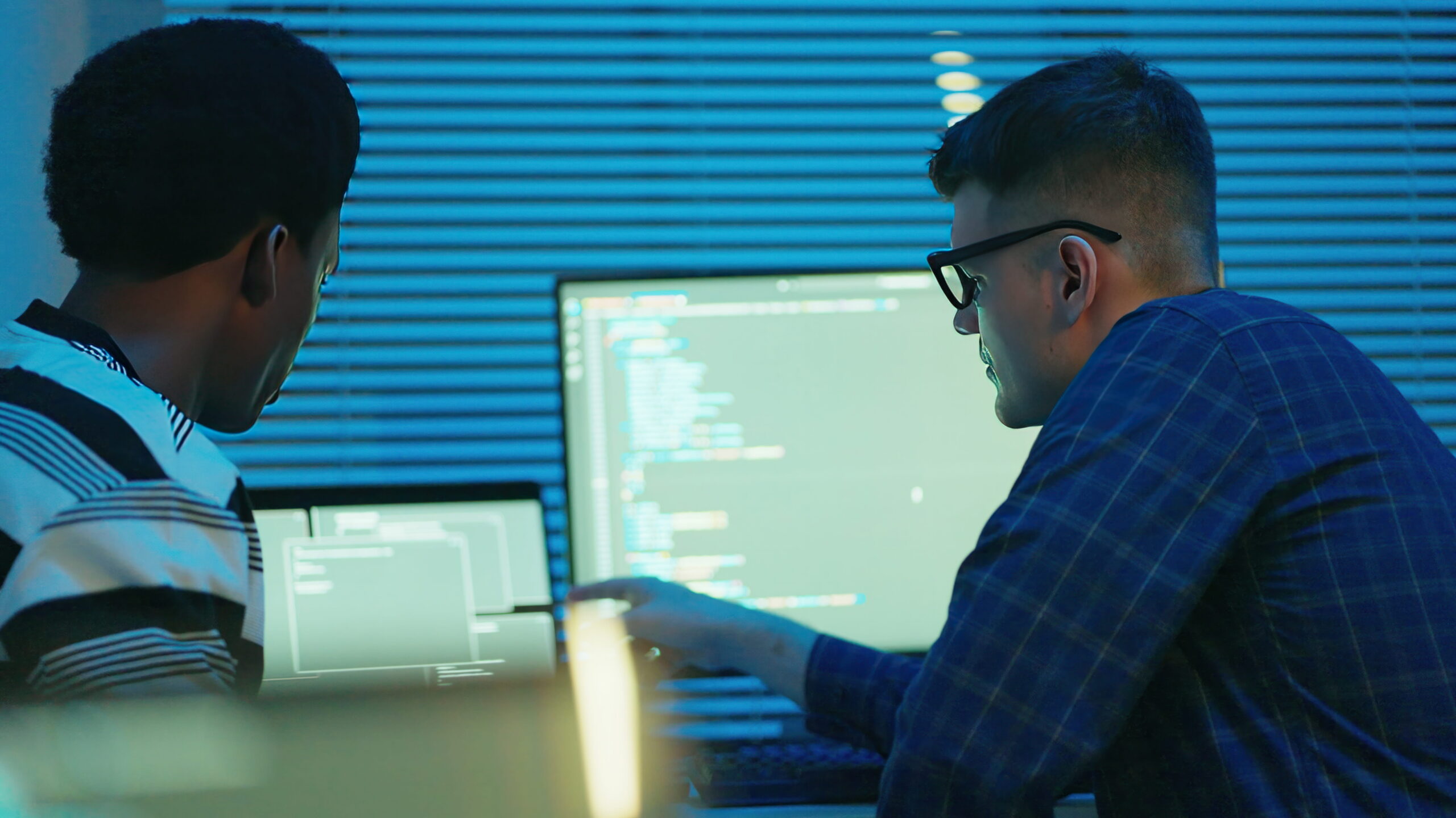 Two men look at the computer with code